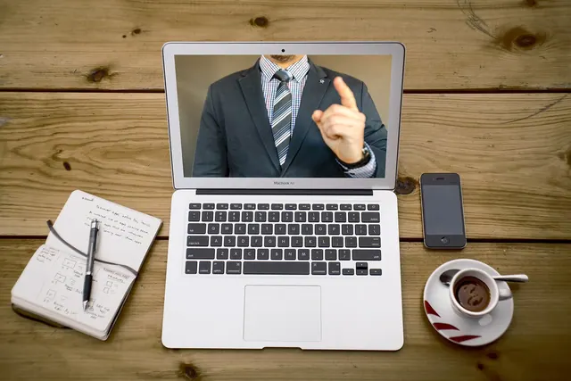 Professional woman engaged in remote work using a laptop with a headset in a modern office.