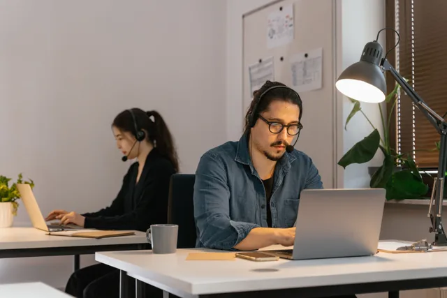 Two call center employees working diligently with headsets in the office. Getting virtual assistant agency services right the first time