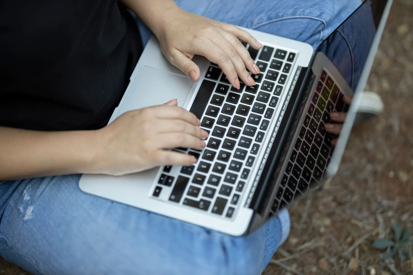 Close-up of a woman typing on a laptop outdoors, focusing on remote work lifestyle. When does a virtual assistant agency owe sales tax in another state?