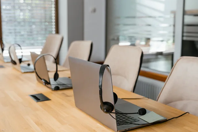 Row of laptops with headsets in a modern office environment ready for communication. Should a virtual assistant agency offer white label services to other firms?